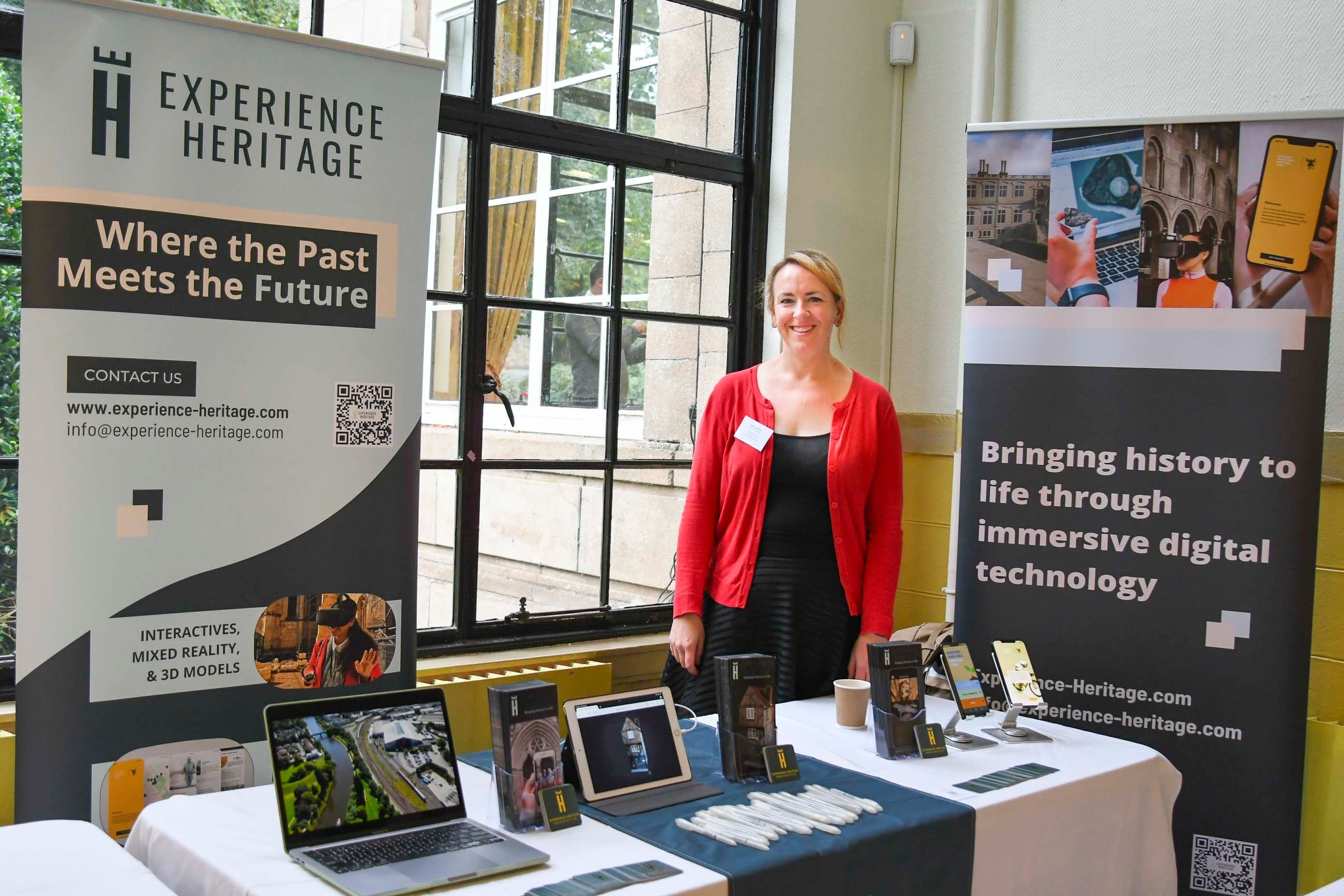 A woman stands behind her exhibitor stall.
