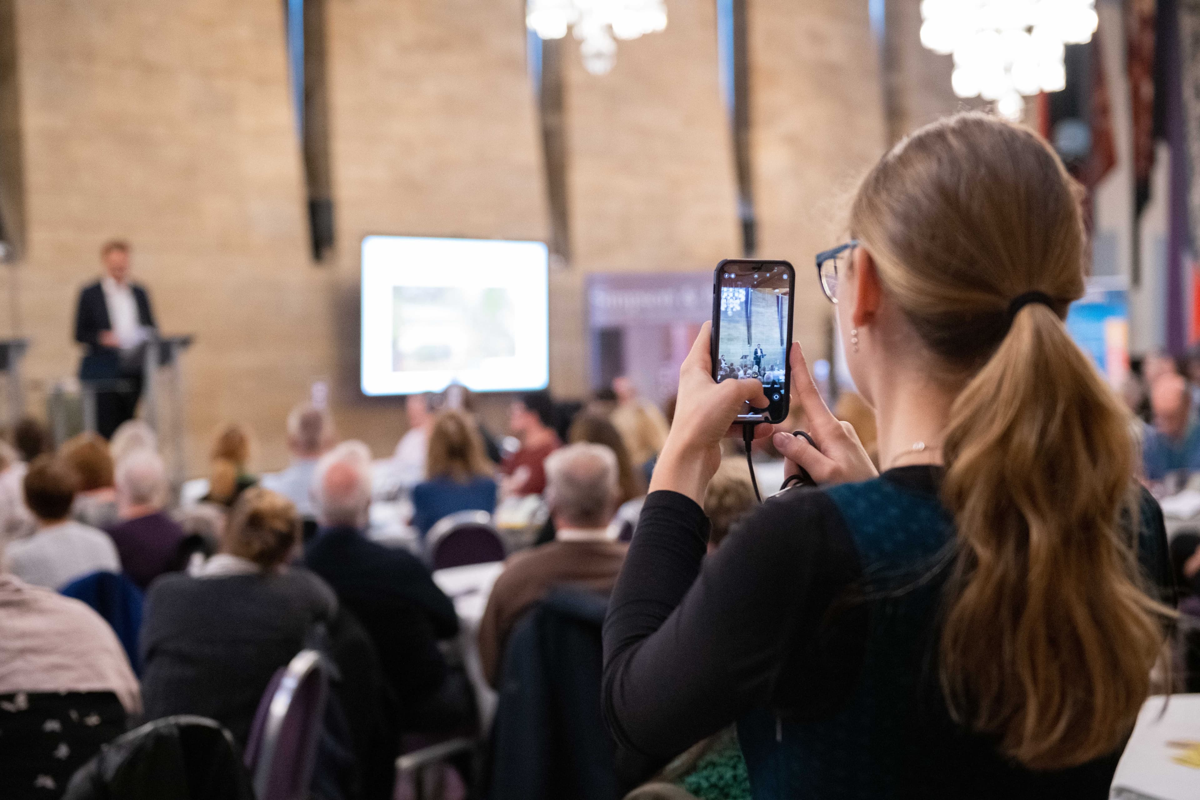 A young Digital Hero films footage on a mobile at the Network's annual conference.